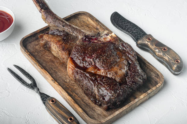 istock Tomahawk beef steak Grilled with spices, on wooden serving board, on white stone  background 1322558481