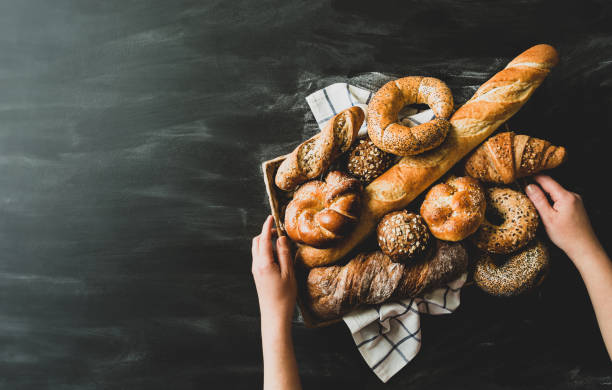 istock Breadstuff - bread rolls, baguette, bagel, sweet bun and croissant on black background 1322559522