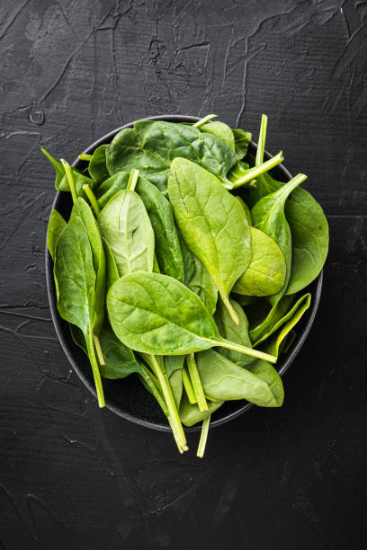 istock Fresh spinach, in bowl, on black stone background, top view flat lay 1322564193