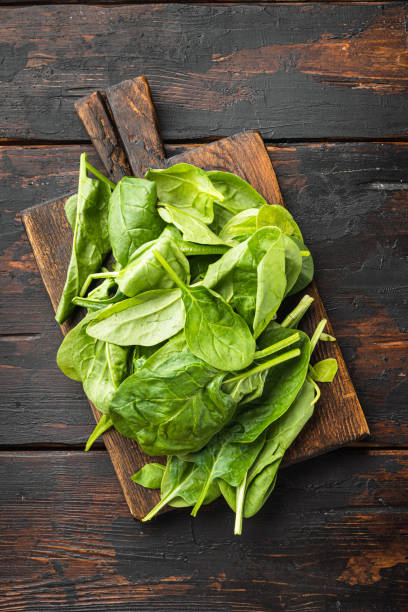 Fresh spinach leaves, on wooden cutting board, on old dark wooden table background, top view flat lay Fresh spinach leaves set, on wooden cutting board, on old dark wooden table background, top view flat lay spinach stock pictures, royalty-free photos & images