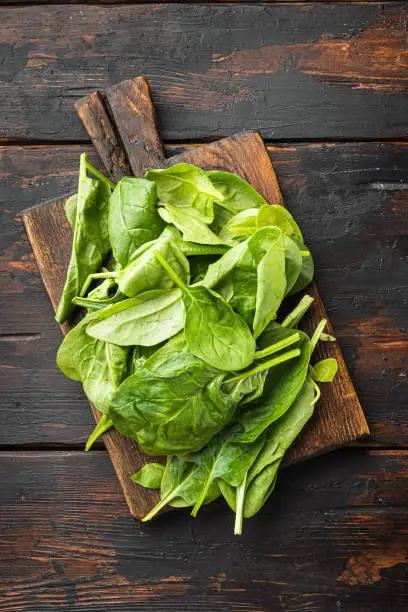 Fresh spinach leaves set, on wooden cutting board, on old dark  wooden table background, top view flat lay