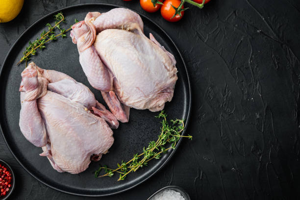 istock Raw coquelet chickens with herbs spices ingredients, on black background, top view with copy space for text 1322565590