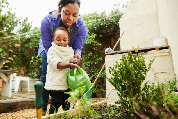 istock Mother and daughter watering backyard garden 1322566674