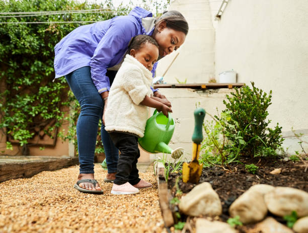 istock Daughter helping mom in watering the garden 1322566675