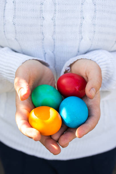 istock Female hands in a white fluffy sweater hold colorful easter eggs 1322567740