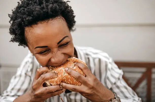 Woman eating stack burger at restaurant