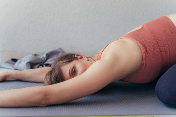 istock Young Woman Looking at Camera while Practicing Yoga, Lying in Child Pose 1322570569