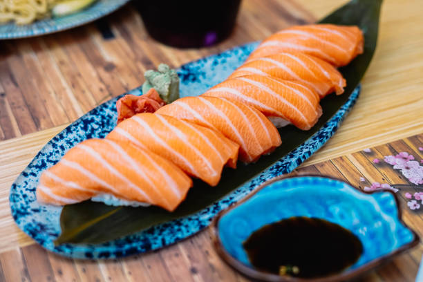plato de niguiri de salmón con salsa de soja en un restaurante de sushi - niguiri sushi fotografías e imágenes de stock
