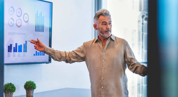 istock Mature businessman giving a presentation with graphs and charts. 1322578677