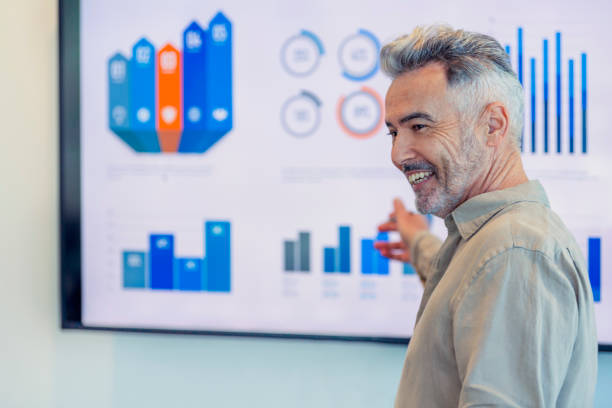 Mature businessman giving a presentation with graphs and charts