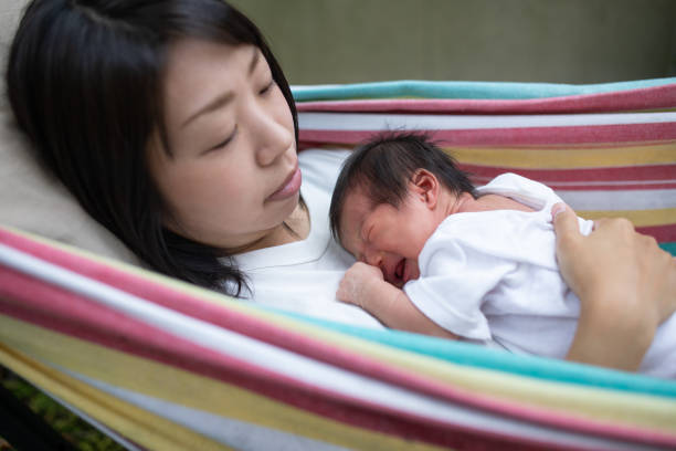 一緒にハンモックで母親の胸の上で眠っている生まれながらの赤ちゃん - 産後うつ 日本人 ストックフォトと画像