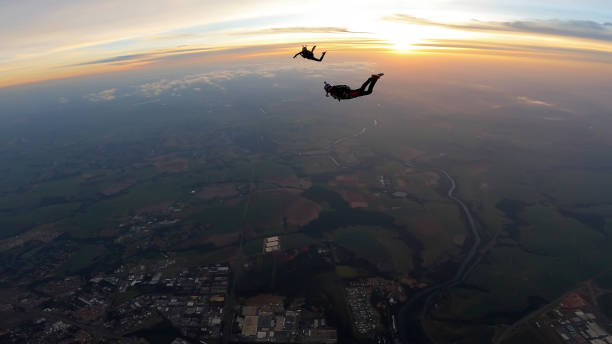 istock Silhouette of skydivers at sunrise 1322581646