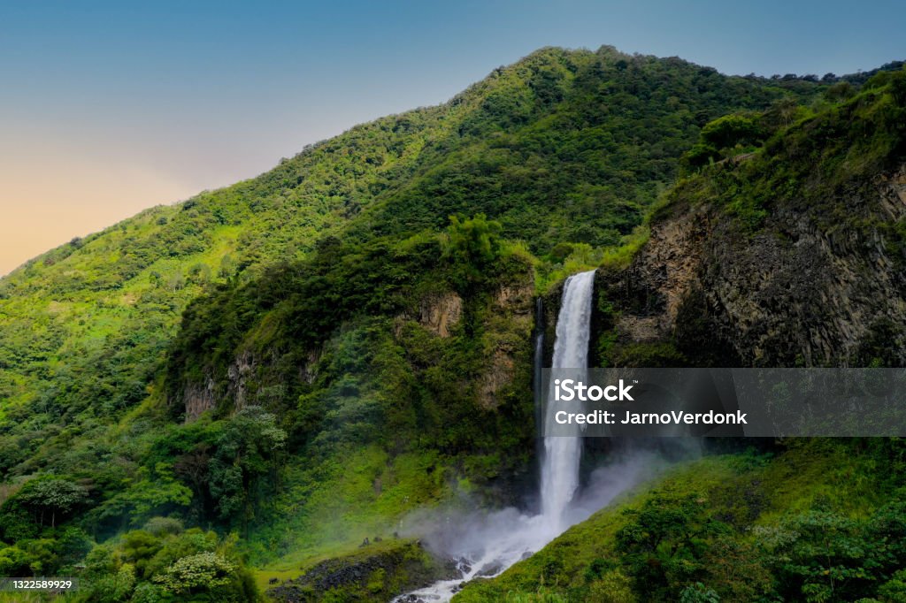 Background of a sideview of a beautifull waterfall in a mountain covered by trees during sunset Background of a sideview of a beautifull waterfall during sunset Ecuador Stock Photo