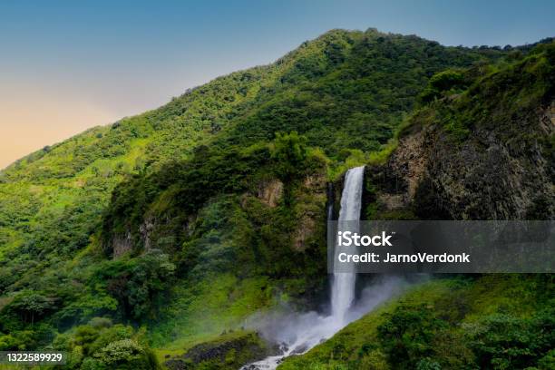 Background Of A Sideview Of A Beautifull Waterfall In A Mountain Covered By Trees During Sunset Stock Photo - Download Image Now
