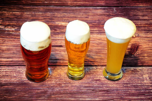 trzy szklanki różnych rodzajów lekkiego piwa są w rzędzie na drewnianym stole. - draught beer variation three objects zdjęcia i obrazy z banku zdjęć