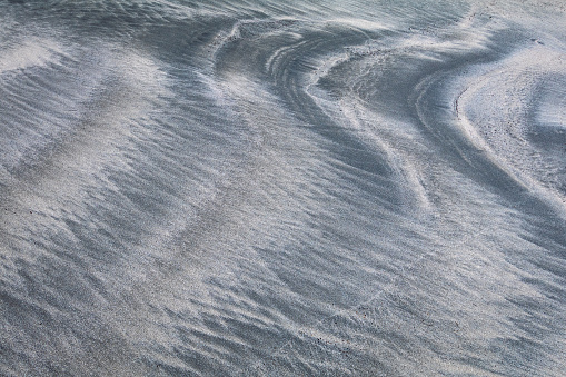 Patterns in the sand along the shoreline.