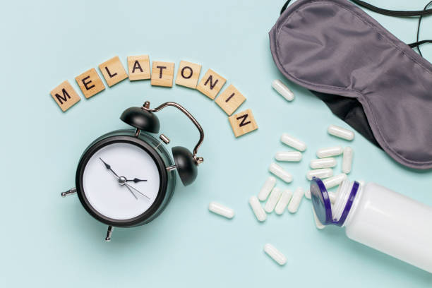 istock White bottle and pills, letters Melatonin,  alarm clock and sleep mask on light grey background. Sleeping backdrop Concept melatonin, insomnia and good night. Top view 1322607959