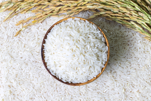 Arroz en cuenco de madera sobre arroz y orejas de arroz fondo, Alimento natural alto en proteínas. photo