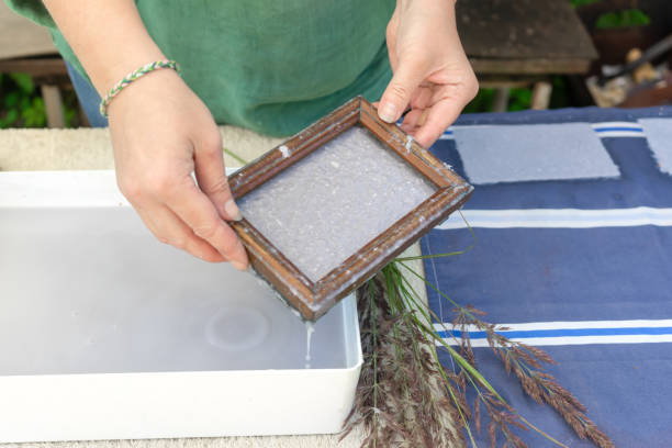 istock Woman holding frame for making paper sheets from waste paper pulp. Selective focus. Decorative and applied art. Recycling concept, ecology. 1322615312