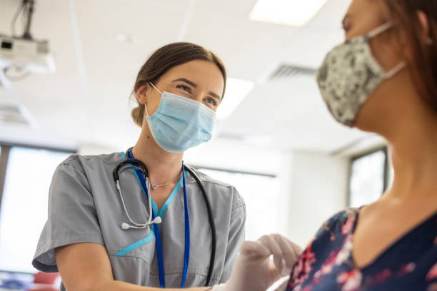 vriendelijke verpleegkundige bereidt patiënt voor op covid-19-vaccinschot - masker stockfoto's en -beelden
