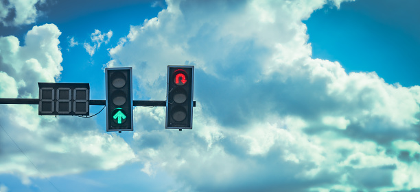 traffic light on green color for go straight and red color for  go turn backward on blue sky in background