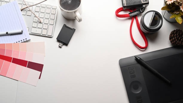 istock Graphic designer workspace with camera, graphic tablet, coffee cup and color swatch on white table. 1322621604