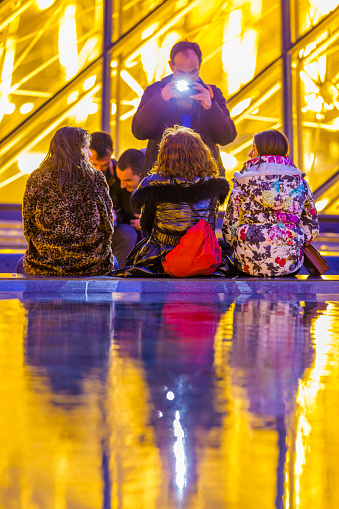 The City of Paris France on March 29, 2014:  Family photograph by the Louvre Museum Pyramid at dusk in Paris France