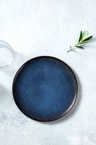 Blue ceramic plate, shot from the top with a glass and an olive branch, Mediterranean cuisine concept with a place for text, a flat lay