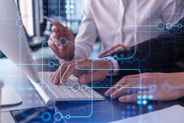 istock Two information technology specialist brainstorming on project to create a new approach to develop software to improve business service. Working with laptop. Tech hologram icons. Formal wear. 1322629995