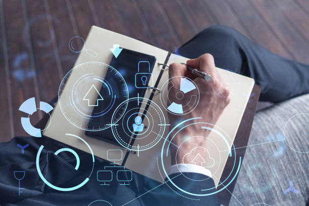 istock Arm in formal wear writing down some ideas using phone to create innovative software to provide a completely new high-tech service. Close up shot. Hologram tech graphs. Concept of Dev team 1322630075