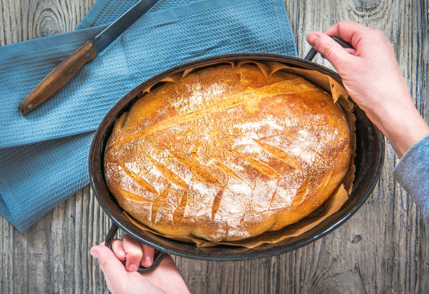 istock Hands holding a pan of freshly baked bread 1322634108