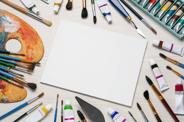 istock Blank canvas, brushes, paints and palette on white wooden table, flat lay. space for text 1322640602