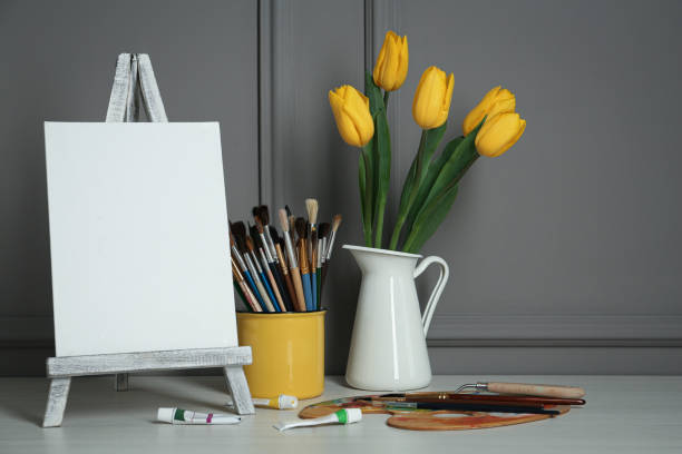 istock Easel with blank canvas, brushes, paints and palette in studio 1322640701