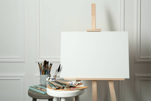 istock Easel with blank canvas, brushes, paints and palette in studio 1322640759