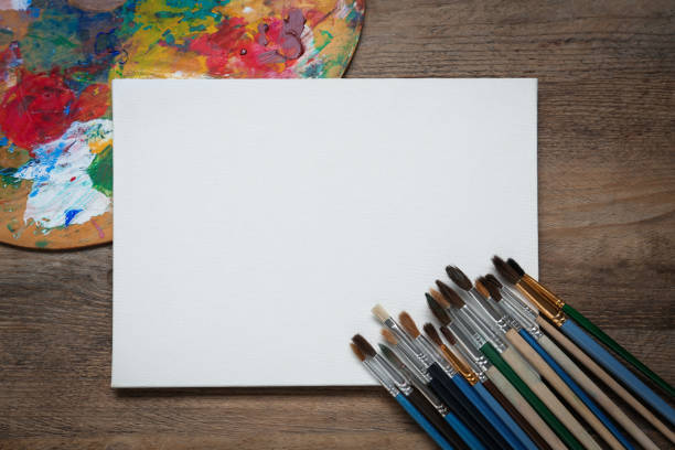 istock Blank canvas, brushes and palette on wooden table, flat lay. Space for text 1322640866