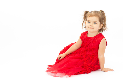 The little girl in brightly red dress on a white background