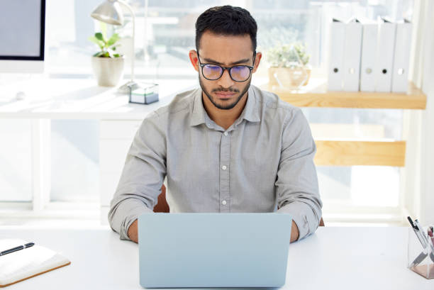 istock Shot of a young man using his laptop at work in a modern office 1322642245