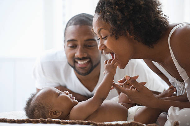 Father watching while baby boy and mother play West New York, NJ 8 weeks stock pictures, royalty-free photos & images