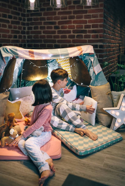 istock Children preparing tent with chairs and bed sheets 1322646092
