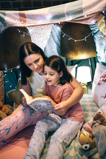 istock Girl reading with her mother in a makeshift tent 1322646100
