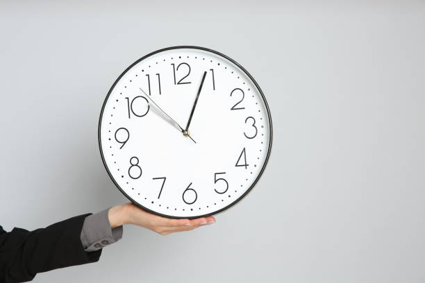 istock Businesswoman holding clock on light grey background, closeup with space for text. Time management 1322647299