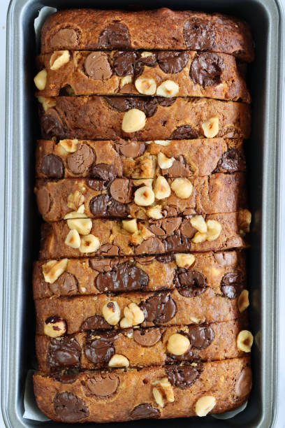 istock Image of cake loaf tin containing thinly sliced, homemade banana bread on white background, elevated view 1322648043