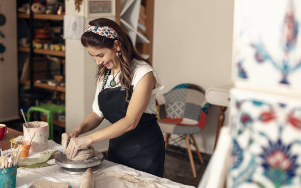 istock Female ceramic artist sculpting clay and making bowls. 1322652149