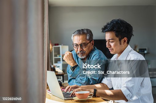 istock Asian senior father and his adult son using laptop computer while sitting at home 1322654040