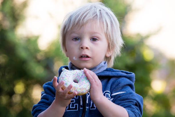 istock Cute child, eating donnuts in garden 1322654095