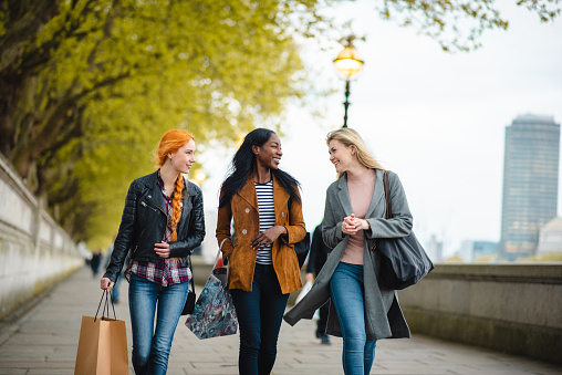 Diverse group of young adult women with shopping bags walking in London