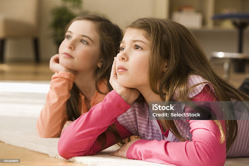 Dos hermanas situadas en el piso mirando hacia arriba - Foto de stock de 8-9 años libre de derechos
