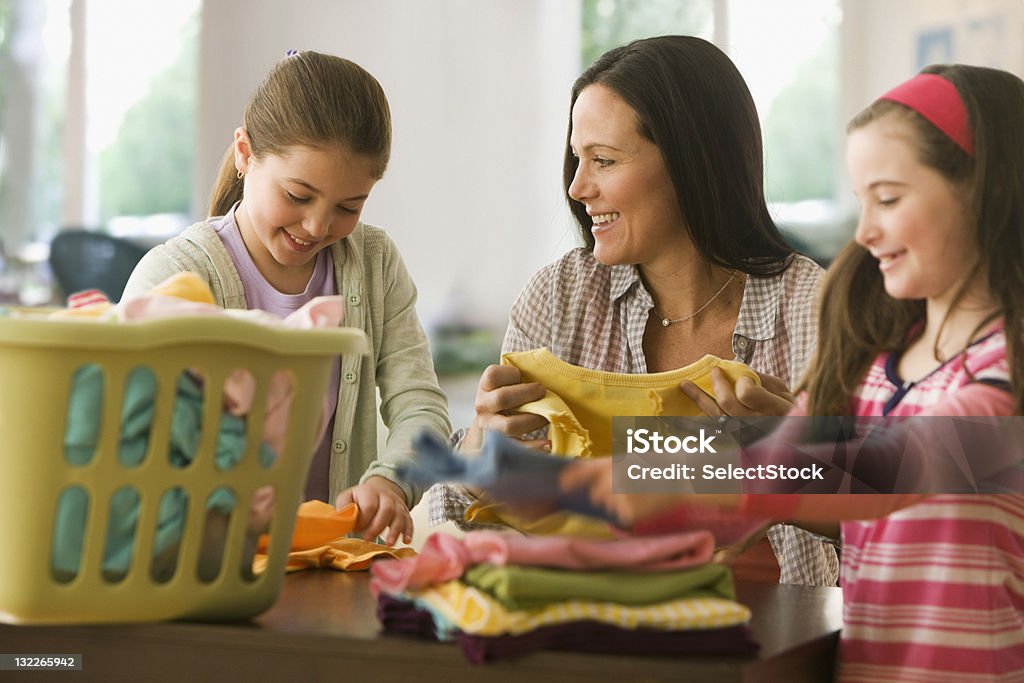 Hermanas madre con ayuda de lavandería y planchado - Foto de stock de Hacer la colada libre de derechos