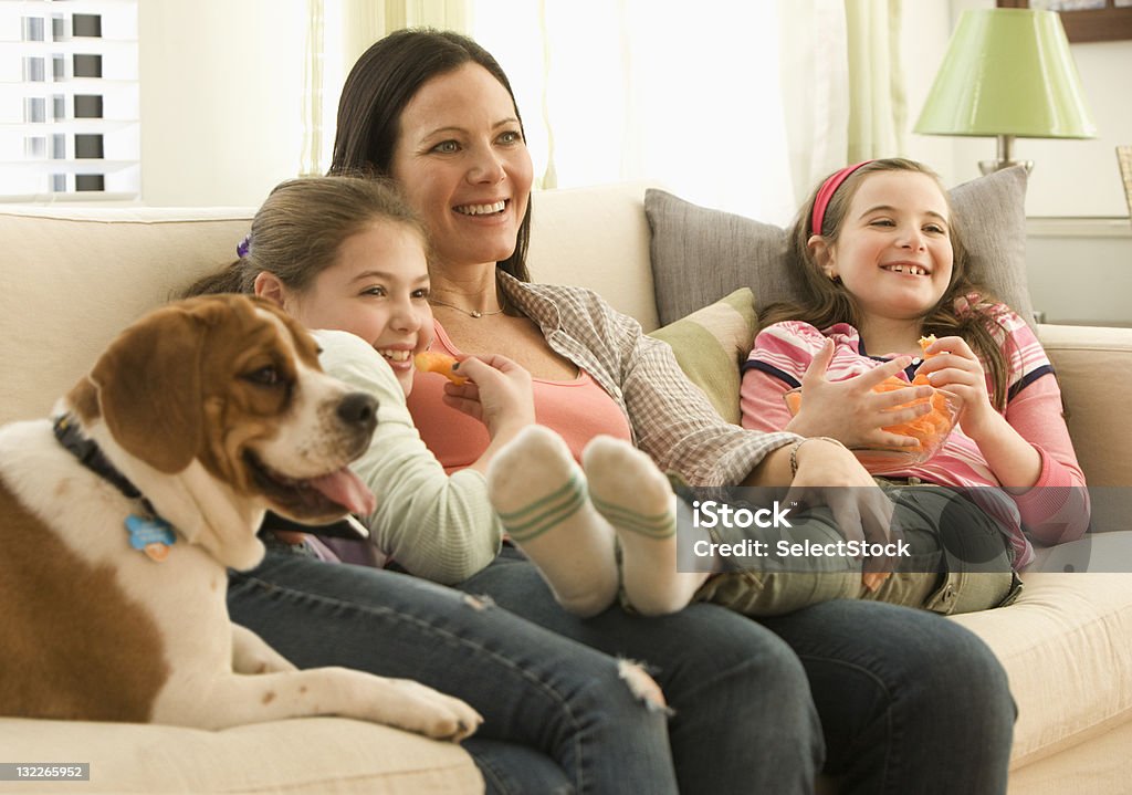 Mãe e filha assistem televisão com a família Cachorro - Foto de stock de Abraçar royalty-free