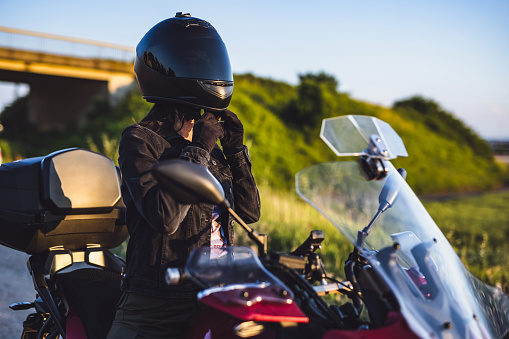 Female motorcyclist adjusting crash helmet